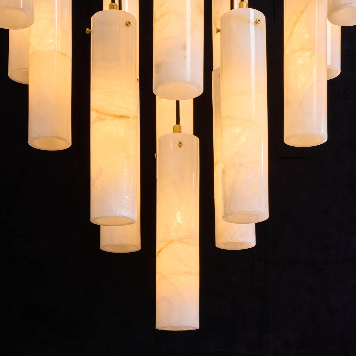 Cylindrical pendant lights with marble-like texture on a black background